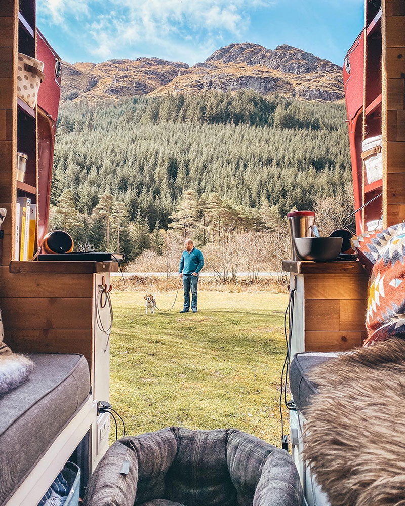 Looking out onto mountains from the back of our campervan whilst wild camping in Scotland